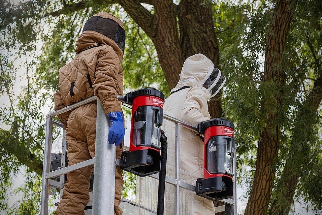 Tweepersoonsteam in beschermende pakken op een hoogwerker tijdens een interventie